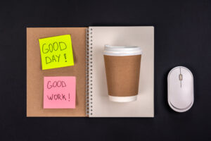 Notebook, disposable cup, mouse and paper colored stickers with motivational inscriptions, top view. The concept of a good job and a good day.